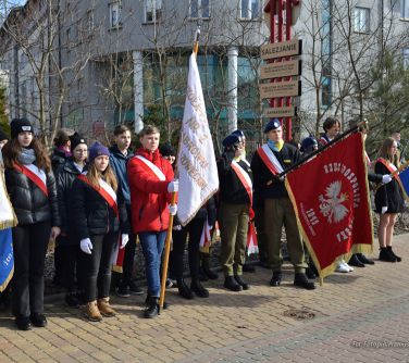 osoby stoją w półkolu, co poniektórzy trzymają sztandary