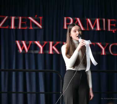 dziewczyna śpiewa na scenie, w tle na czarnym suknie z napisem Dzień Pamięcie Żołnierzy Wykletych