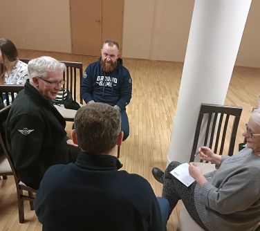 osoby siedzą w kole na krzesłach