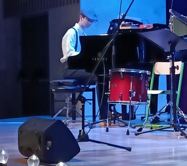 chłopiec w stroju z lat 20-tych gra na pianinie