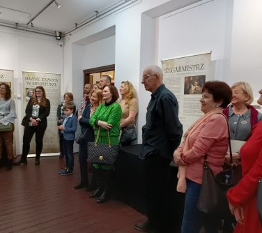 osoby stoją w skupieniu słuchają gry na fortepianie