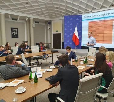 osoby siedza przy stole podczas konferencji