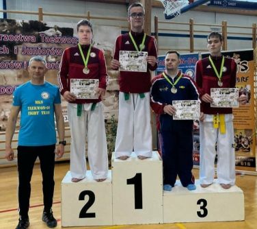 osoby pozują do zdjęcia stojąc na podium, obok mężczyzna