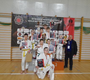 dzieci pozuja na podium obok trener