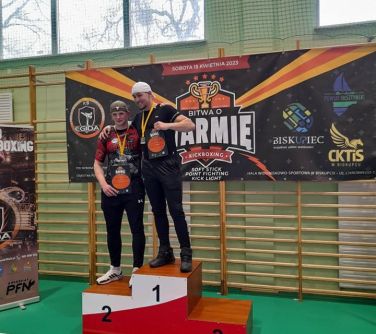 dwóch nastolatków pozuje na podium, w tle baner