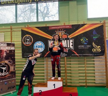 nastolatka pozuej na podium, obok mężczyzna wskazujący na nią