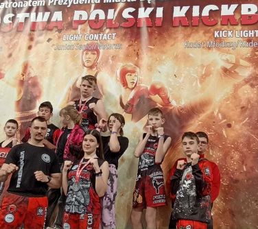 zawodnicy z trenerem pozuja do zdjęcia w tle baner