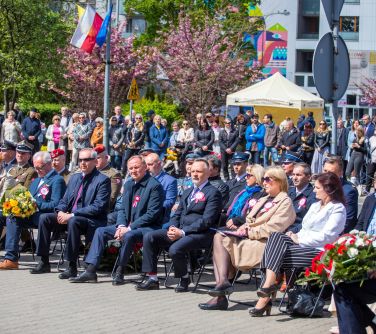 zgromadzone osoby na uroczystości siedzą na krzesłach, w tle osoby stojące