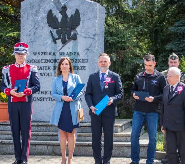 osoby pozują do zdjęcia przed pomnikiem