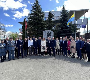 osoby pozują do zdjęcia przed pomnikiem