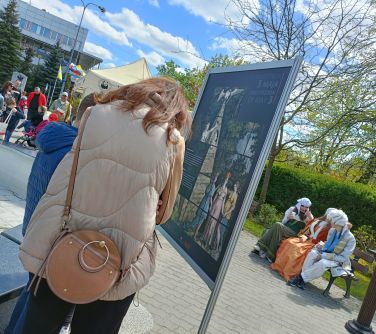 osoby czytają informacje na tablicy, w tle osoby