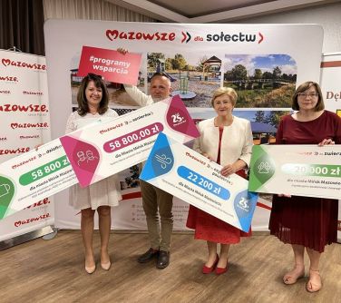 osoby pozują do zdjęcia trzymając tablice z kwotami w dłoniach
