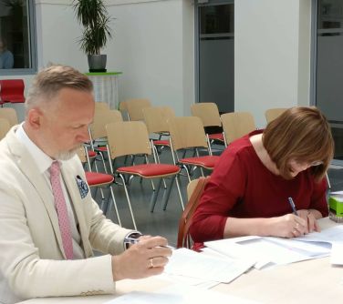 kobieta i mężczyzna podpisują dokumenty przy stole