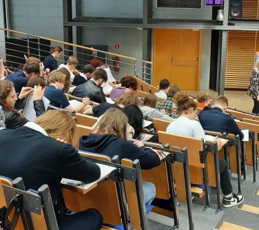 ławki w półkolu i w podwyższeniu na co poniektórych siedzą osoby
