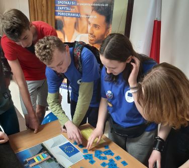 osoby uzupełniają puzzle leżące na stole