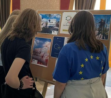 osoby oglądają zdjęcia wywieszone na tablicy