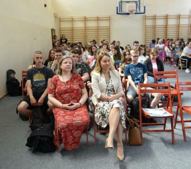 osoby siedzą na krzesłach na auli