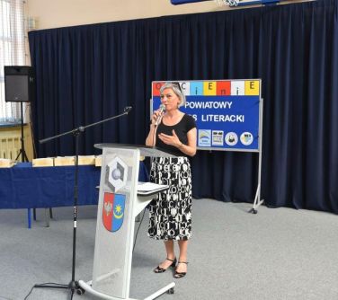 kobieta przemaiwa przed przeźroczystą mównicą