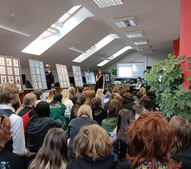 zgromadzeni ludzie siedzą, naokoło prace na stelarzach