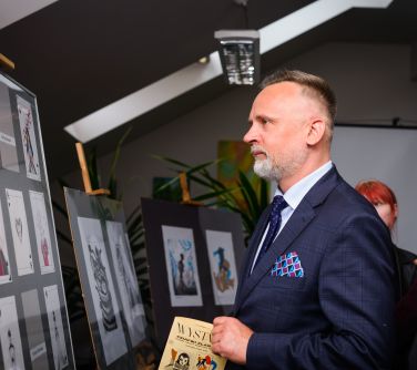 zamyślony mężczyzna okląda prace plastyczne