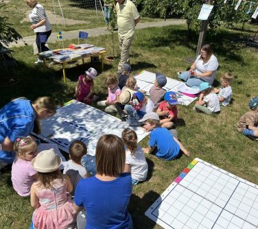 osoby siedzą na ziemi, na planszach malują