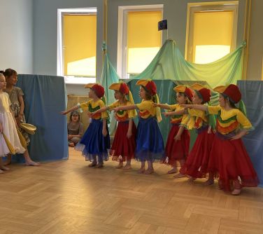 dzieci w kolorowych przebraniach w szkole robią przedstawienie