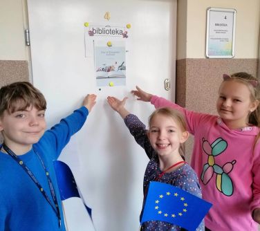 trójka dzieci wskazuje napis na dzwiach