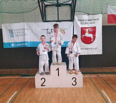 dzieci stoja na podium trzymając dyplomy w dłoniach