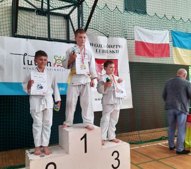 chłopcy pozują do zdjęcia stojąc na podium, trzymają dyplomy w dłoniach