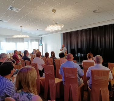 widok na publiczność, która  słucha wypowiedzi dyrektora Muzeum Ziemi Mińśkiej stojącego na scenie