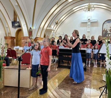 wnętrze kościoła występ chóru, na przodzie chłopiec i dziewczynka śpiewają do mikrofonu