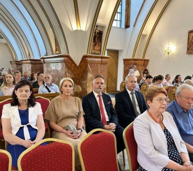 wnętrze kościoła, na krzesłach przed ławkami siedzą osoby