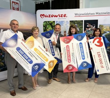 osoby pozują do zdjęcia trzymając w dłoniach plansze z kwotami dofinansowania