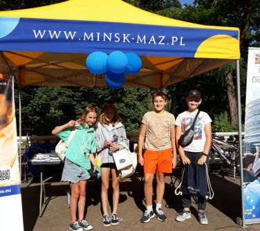 czworo dzieci pozuje do zdjęcia stojąc pod zółto-niebieskim namiotem promocyjnym