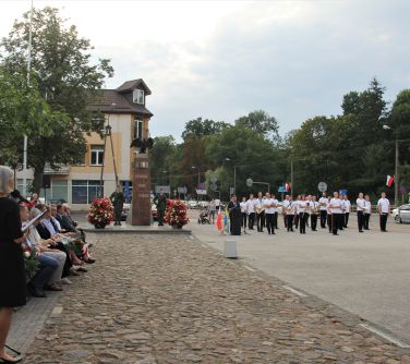 widok na zgromadzonych gosci, przemaiwiającego burmistrza, pomnik i orkiestrę
