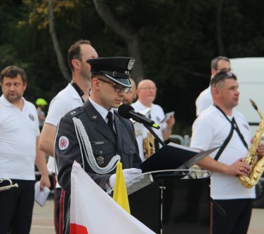 żołnierz w galowym mundurze stoi przy mównicy i odczytuje apel pamięci