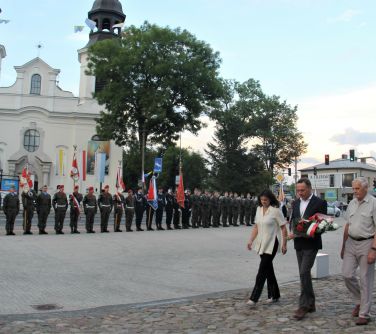 dwóch mężczyzn i kobieta idą w kierunku pomnika niepodległości złożyć wieniec