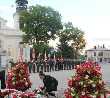 kobieta składa wieniec przy pomniku niepodległości