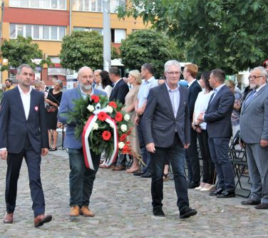 trzech mężczyzn idzie w kierunku pomnika niepodległości złożyć wieniec