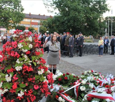 młoda kobieta w mundurze harcerskim stoi przy pomniku niepodległości