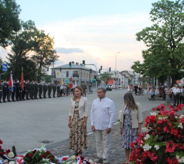 dwie kobiety oraz mężczyzna stoją przy pomniku niepodległości
