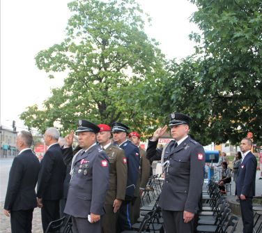 mężczyźni w mundurach stojący wśród publiczności salutują