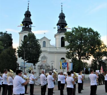 orkiestra dęta gra utwór, w tle budynek kościola
