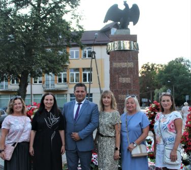 kobiety i meżczyzna pozują do zdjecia przes pomnikiem niepodległosci