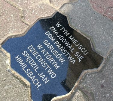 zdjęcie tablicy z napisem wmurowanej w chodnik z kostki