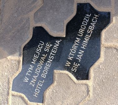 zdjęcie podwójnej tablicy wmurowanej w chodnik z kostki