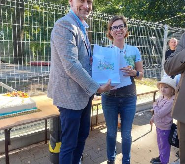 usmiechnięta kobieta i mężczyzna pozują do zdjęcia trzymają torebę papierową z kolorowym nadrukiem w dłoniach, obok stoją...