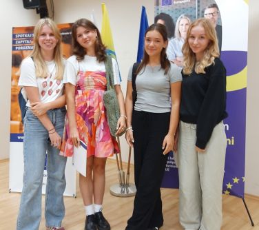 grupa czterech dziewcząt pozuje do zdjęcia na tle banerów