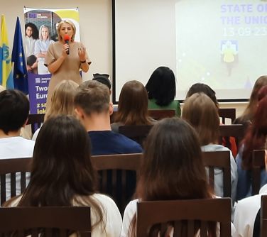kobieta przemawia do zgromadzonej młodzieży, widok zza pleców publiczności