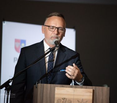 mężczyzna przemawia do mikrofonu przy mównicy